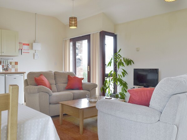 A living room with a sofa, a coffee table, a television, and a plant.