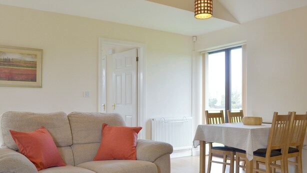 A living room with a sofa, a coffee table, and a dining area with chairs and a table.