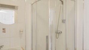 A modern bathroom with a glass-enclosed shower, a sink, and a mirror.