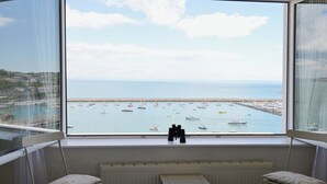 A bedroom with a large window overlooking a marina with boats. - 2 bedroom accommodation in Brixham (Brixham)