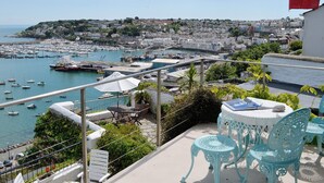 A balcony with a view of a harbor, a flag, and outdoor furniture. - 2 bedroom accommodation in Brixham (Brixham)
