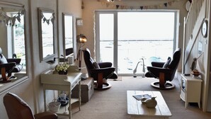 A living room with a large window, two leather chairs, a white coffee table, and a small white table with a lamp. - 2 bedroom accommodation in Brixham (Brixham)