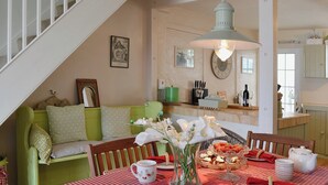 A dining area with a checkered tablecloth, a vase of flowers, and a kitchen in the background. - 2 bedroom accommodation in Brixham (Brixham)