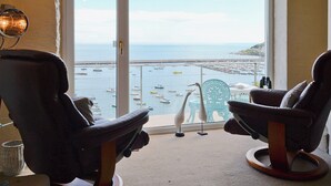 A room with two chairs facing a large window overlooking a marina with boats. - 2 bedroom accommodation in Brixham (Brixham)