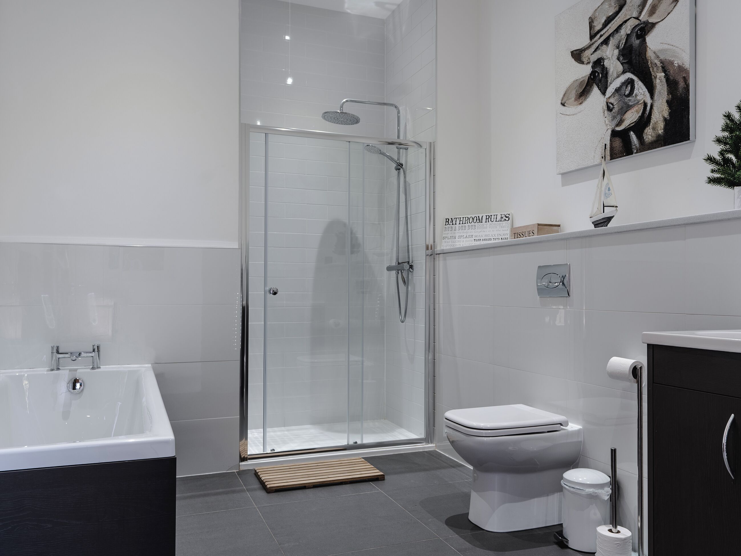 A modern bathroom with a glass-enclosed shower, a white bathtub, and a toilet.