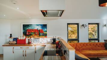 Una cocina moderna con una isla central, un área de comedor con sofá y un cuadro de casas en la pared.