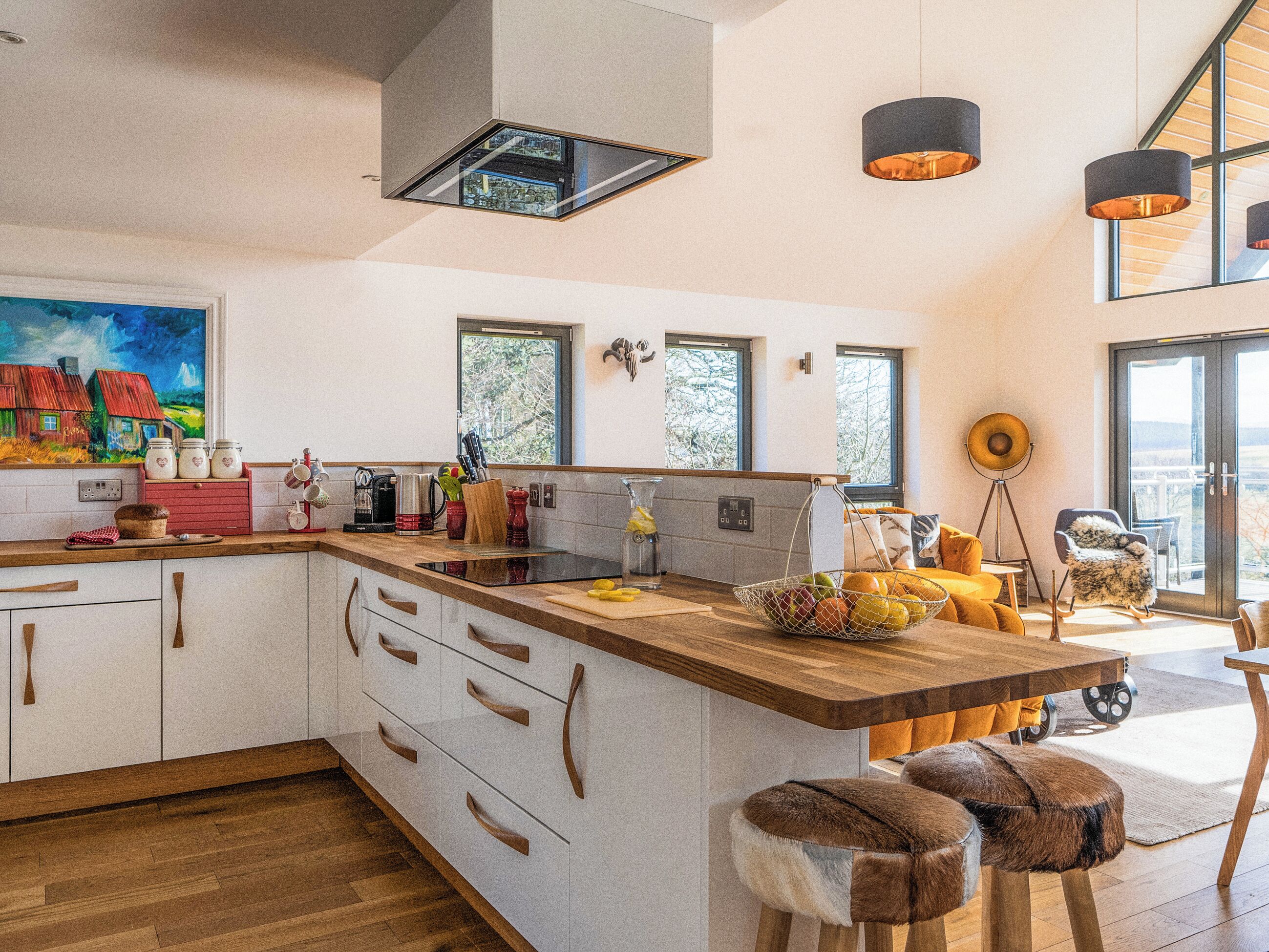 A modern kitchen with a central island, wooden cabinets, and a large window.