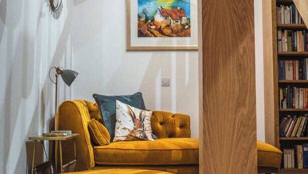 Un salon avec un canapé, une lampe, un tableau et une bibliothèque.