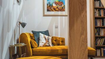 A living room with a sofa, a lamp, a painting, and a bookshelf.