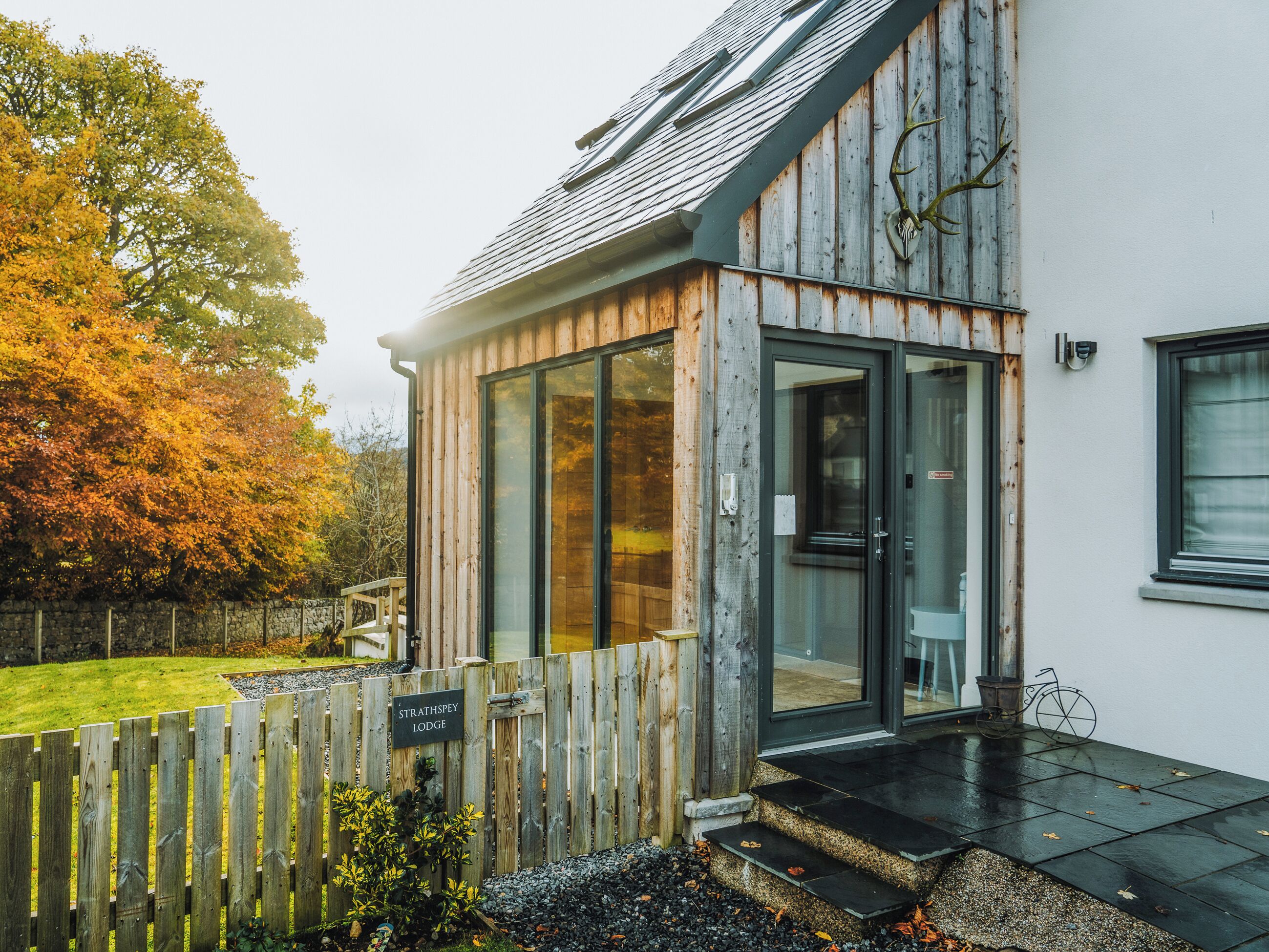 A lodge with a wooden exterior, a glass door entrance, and a stone pathway leading to the door.
