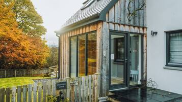 A lodge with a wooden exterior, a glass door entrance, and a stone pathway leading to the door.