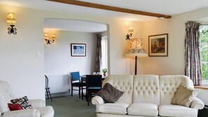 A living room with a sofa, chairs, a dining table, and a lamp. - 1 bedroom accommodation in Dalwood, near Axminster (Dalwood, near Axminster)