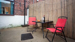 An outdoor patio area with a table and two red chairs, a bottle of wine, and a loaf of bread. - 2 bedroom accommodation in Shildon, near Bishop Auckland (Shildon, near Bishop Auckland)