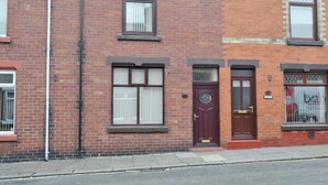 A two-story brick house with a front door, two windows with shutters, and a small porch. - 2 bedroom accommodation in Shildon, near Bishop Auckland (Shildon, near Bishop Auckland)