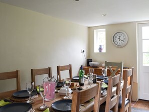 A dining area with a wooden table set for four, including plates, glasses, and a pitcher. - 4 bedroom accommodation in Lymington (Lymington)