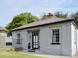 A white building with a black door, windows, and a chimney.