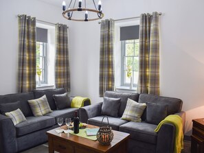 A living room with a grey sofa, a wooden coffee table, and a chandelier.