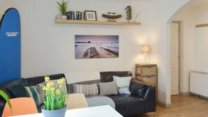 A living room with a black leather sofa, a white table, and a blue potted plant. - 2 bedroom accommodation in Woolacombe (Woolacombe)