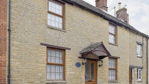 A traditional stone building with a wooden door, multiple windows, and a small porch. - 3 bedroom accommodation in Bampton, near Witney (Bampton, near Witney)