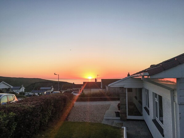 A residential area with houses, a driveway, and a sunset in the background.