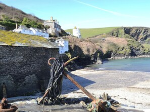 A coastal scene with a stone wall, a wooden post with ropes, and buildings on a hillside. - 3 bedroom accommodation in Port Isaac, near Wadebridge (Port Isaac, near Wadebridge)