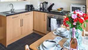 Une cuisine moderne avec des meubles en bois, un évier en acier inoxydable, une cuisinière à gaz et un four à micro-ondes.