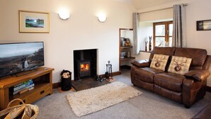 Una sala de estar acogedora con chimenea, un sofá de cuero, un televisor y una repisa con adornos decorativos.