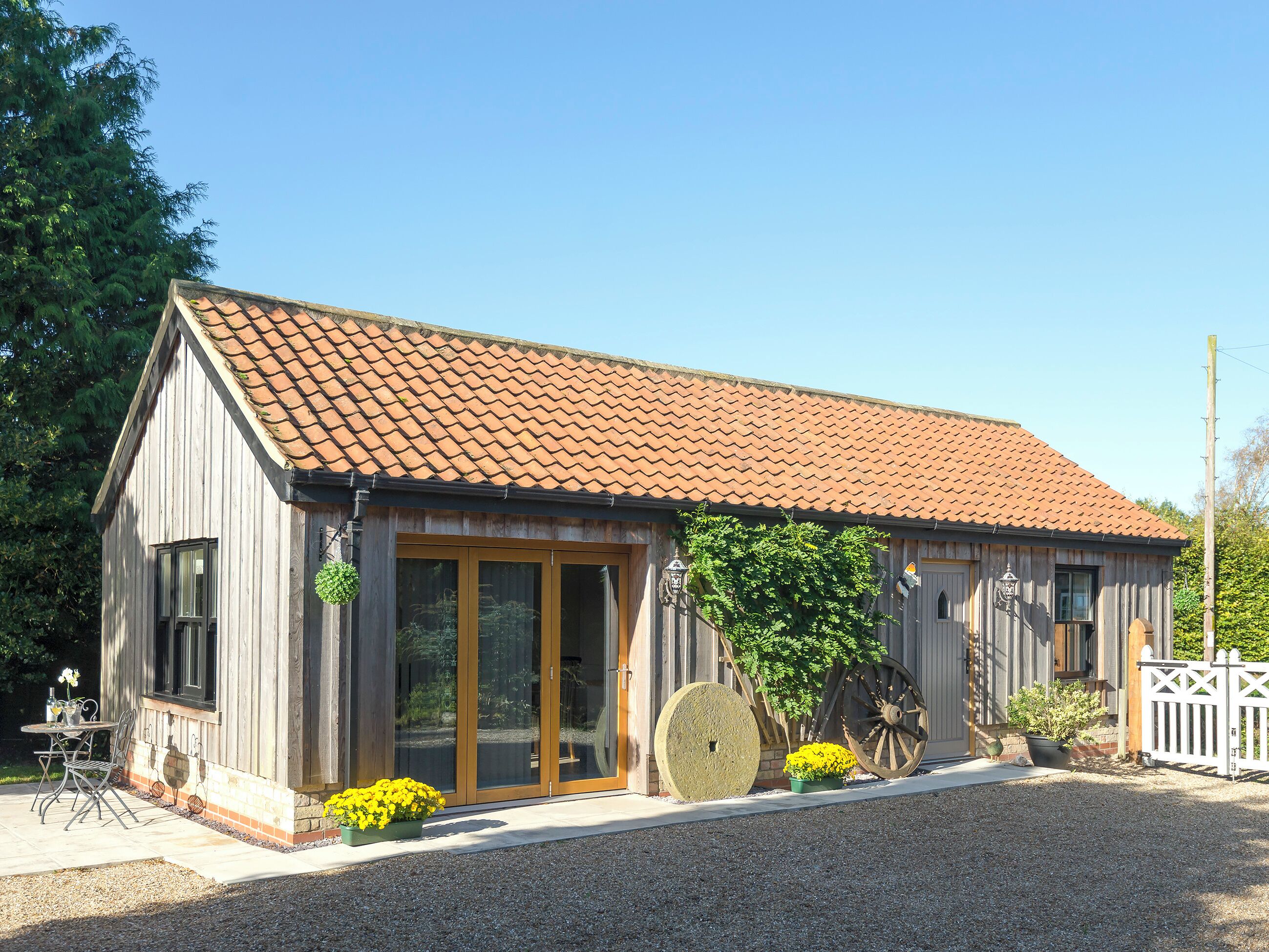 A wooden building with a tiled roof, large windows, and a gravel driveway.