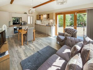 A modern kitchen with a dining area, a sofa, and a view of the garden.