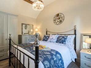 Ein Schlafzimmer mit Bett, Nachttischen, einem Schminktisch, einem Spiegel und einer Deckenleuchte.