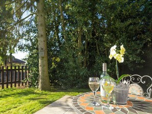 Een tafel met een fles en twee glazen, omringd door groen.