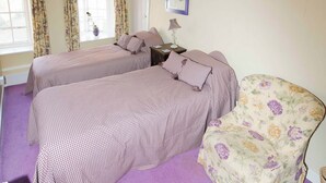 A room with two beds, a chair, a lamp, and a window with curtains. - The Plover - UKC2845 (Blakeney, near Holt)