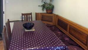 A dining table with a polka dot tablecloth, a black bowl, and two chairs. There are two framed pictures on the wall and a potted plant. - The Plover - UKC2845 (Blakeney, near Holt)