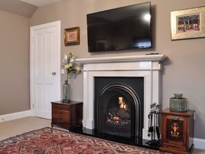 Una sala de estar con chimenea, un televisor de pantalla plana montado encima y una alfombra estampada.
