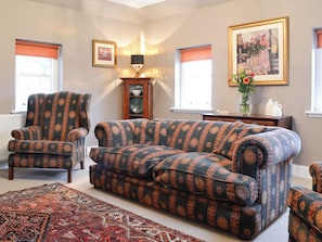 Una sala con un sofá estampado, un sillón y una alfombra.