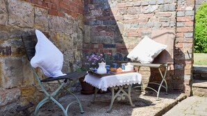 A rustic outdoor seating area with a table set for a meal, a chair, and a bench. - Cowbeech Farm Cottage (Cowbeech, near Hailsham)