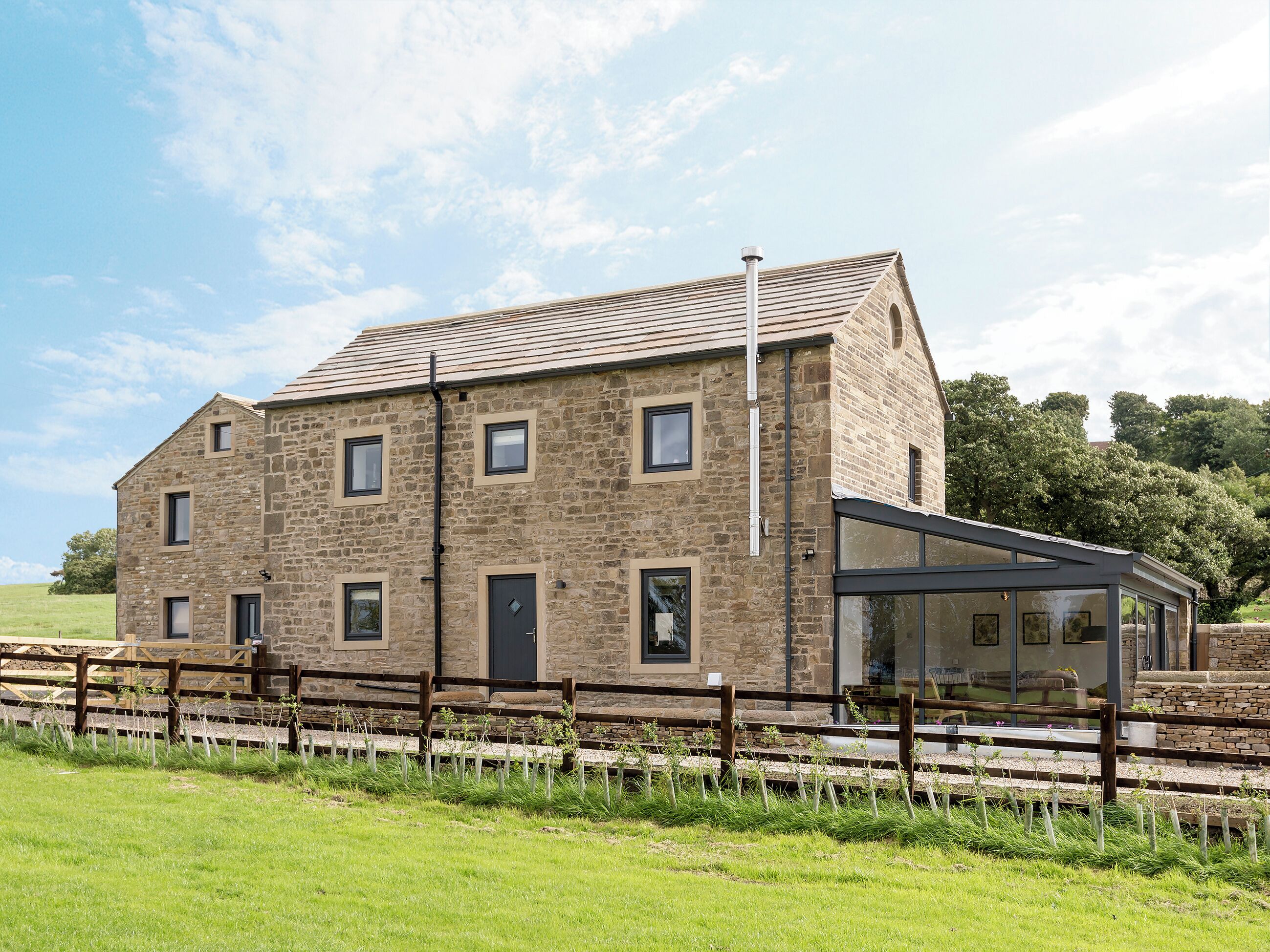 A stone building with multiple windows, a door, and a covered outdoor area.