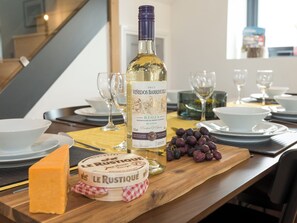 A table set with a bottle of wine, a cheese wheel, and grapes. - Moorgate Cottage - UKC3380 (Kelbrook, near Barnoldswick)