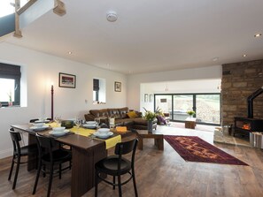 A spacious living area with a dining table, leather sofa, and a fireplace. - Moorgate Cottage - UKC3380 (Kelbrook, near Barnoldswick)