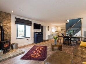 A living room with a fireplace, a sofa, a rug, and a dining area with chairs and a table.