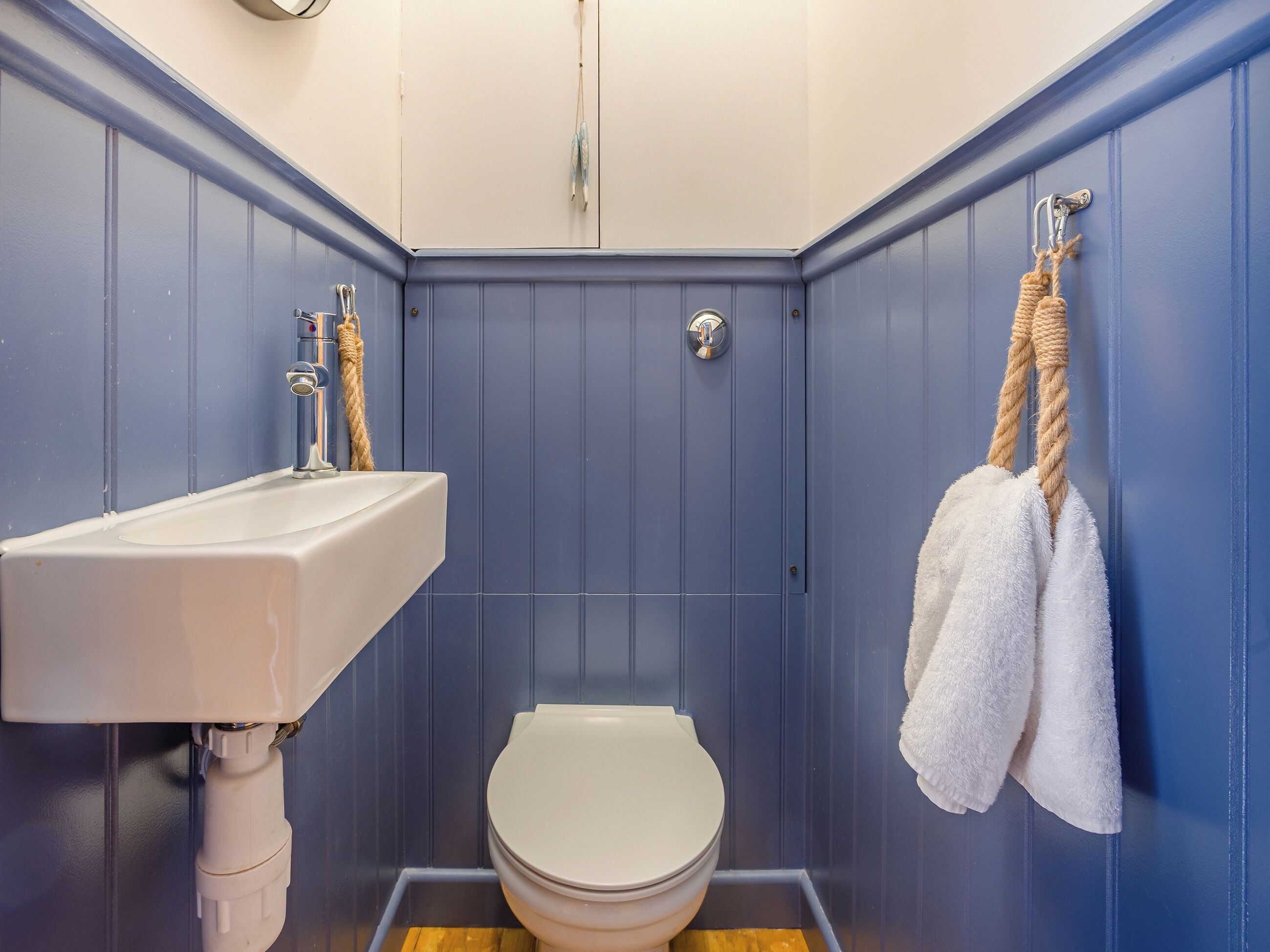 A small bathroom with a white sink, a toilet, and a towel rack with two towels.