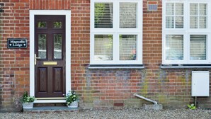A brick building with a dark wooden door, a sign reading "Magnolia Lodge," and a window with a white frame. - 2 bedroom accommodation in Sheringham (Sheringham)