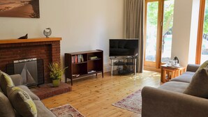A living room with a fireplace, a bookshelf, a television, and a sofa. - 2 bedroom accommodation in Sheringham (Sheringham)