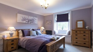 Une chambre à coucher comprenant un lit, des tables de chevet, une commode, une fenêtre avec vue et un lustre.
