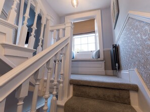 Eine Treppe mit weißen Balustraden, ein Fenster mit Blick und ein Heizkörper an der Wand.
