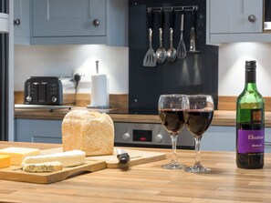 Una cocina con pan, queso, dos copas de vino y una botella de vino.