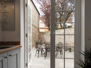 A kitchen with a large window, a dining area with chairs and a table, and a brick wall outside.