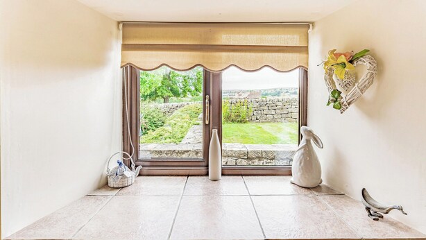Una habitación con un amplio ventanal, una pared de piedra en el exterior y una decoración de corazón de mimbre en la pared.