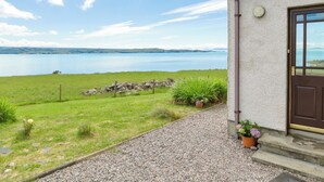 A house with a gravel pathway leading to a door, a stone wall, and a view of a lake. - 3 bedroom accommodation in Gairloch (Gairloch)
