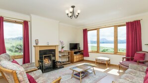 A living room with a fireplace, sofa, armchair, and a television. - 3 bedroom accommodation in Gairloch (Gairloch)